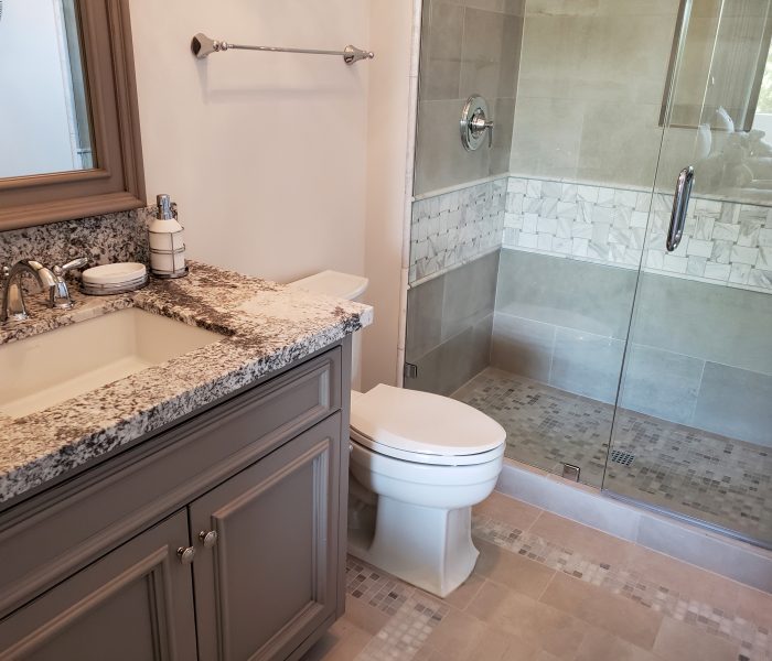 transitional style bathroom vanity in gray with speckled white and black countertops