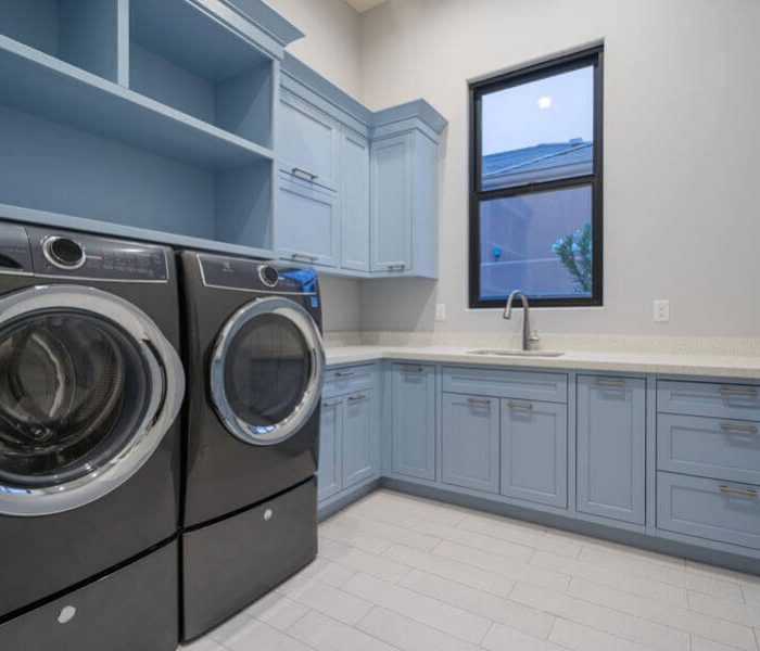 transitional style laundry room in blue with white quartz countertops