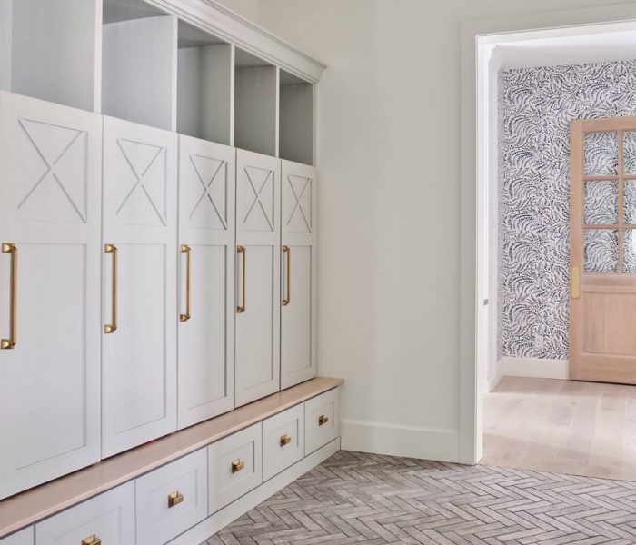 shaker style mudroom cabinetry in white with natural wood and brass accents